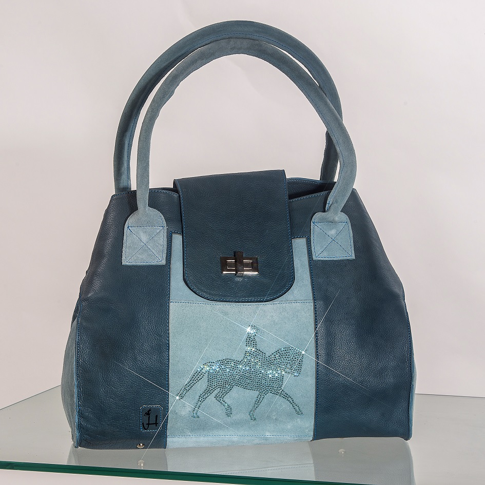 Il modello “Harmonia” è la shopper dedicata al dressage, una borsa capiente in vitello e crosta, qui proposta nella variante azzurro/indaco, con cristalli swarovsky in tinta e comoda tracolla asportabile. Gli ampi manici in crosta permettono di indossarla comodamente a spalla.